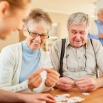 Clermont Park Senior Living Community in Denver, CO - clermont park senior adults playing game with caregiver