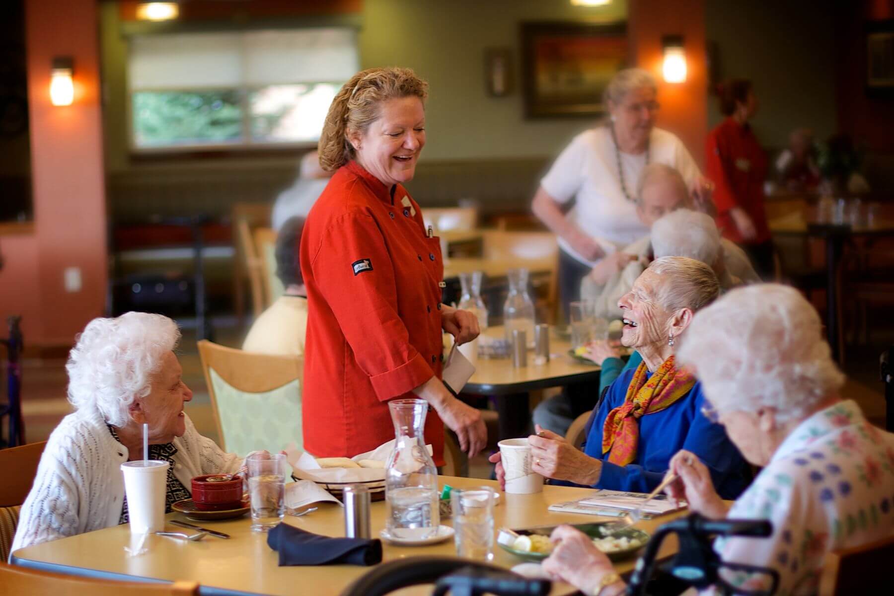 Clermont Park Senior Living Community in Denver, CO - older adults and dining team member talk at mealtime